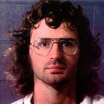 a mugshot of david koresh, who wears glasses and looks directly into the camera