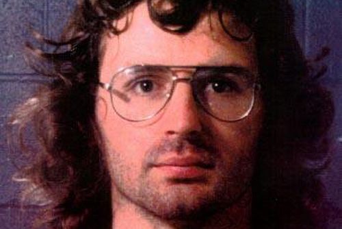 a mugshot of david koresh, who wears glasses and looks directly into the camera