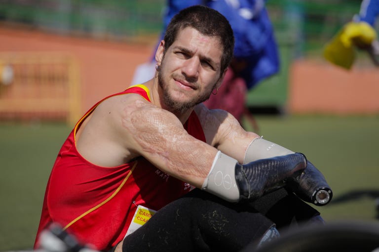 un atleta con prótesis en las manos sentado en una pista de atletismo