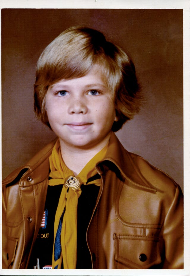 a young child wearing a tan leather jacket and a yellow scarf