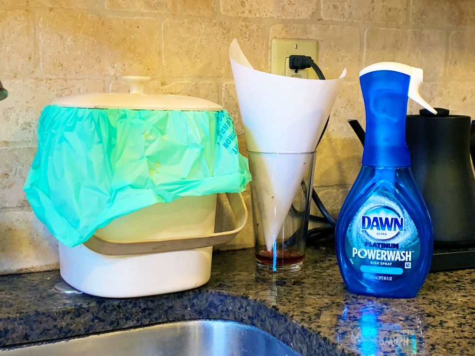 kitchen sink with dawn powerwash, a bamboo compost bin, and a homemade fruit fly trap consisting of a glass with vinegar in the bottom and a paper cone