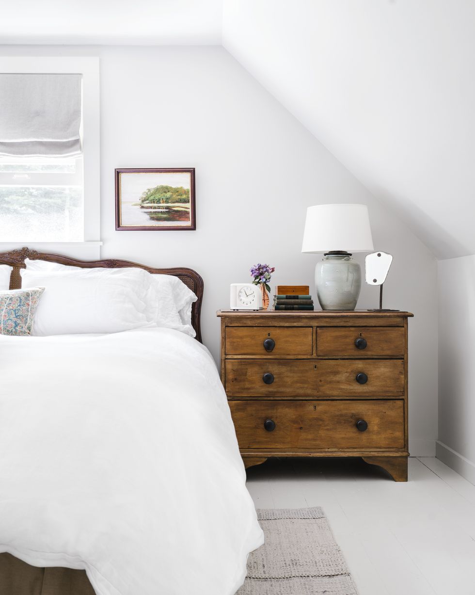 white bedroom with antique wood bed and dresser