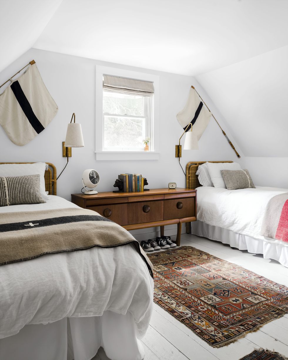 all white bedroom with twin rattan beds and vintage rugs