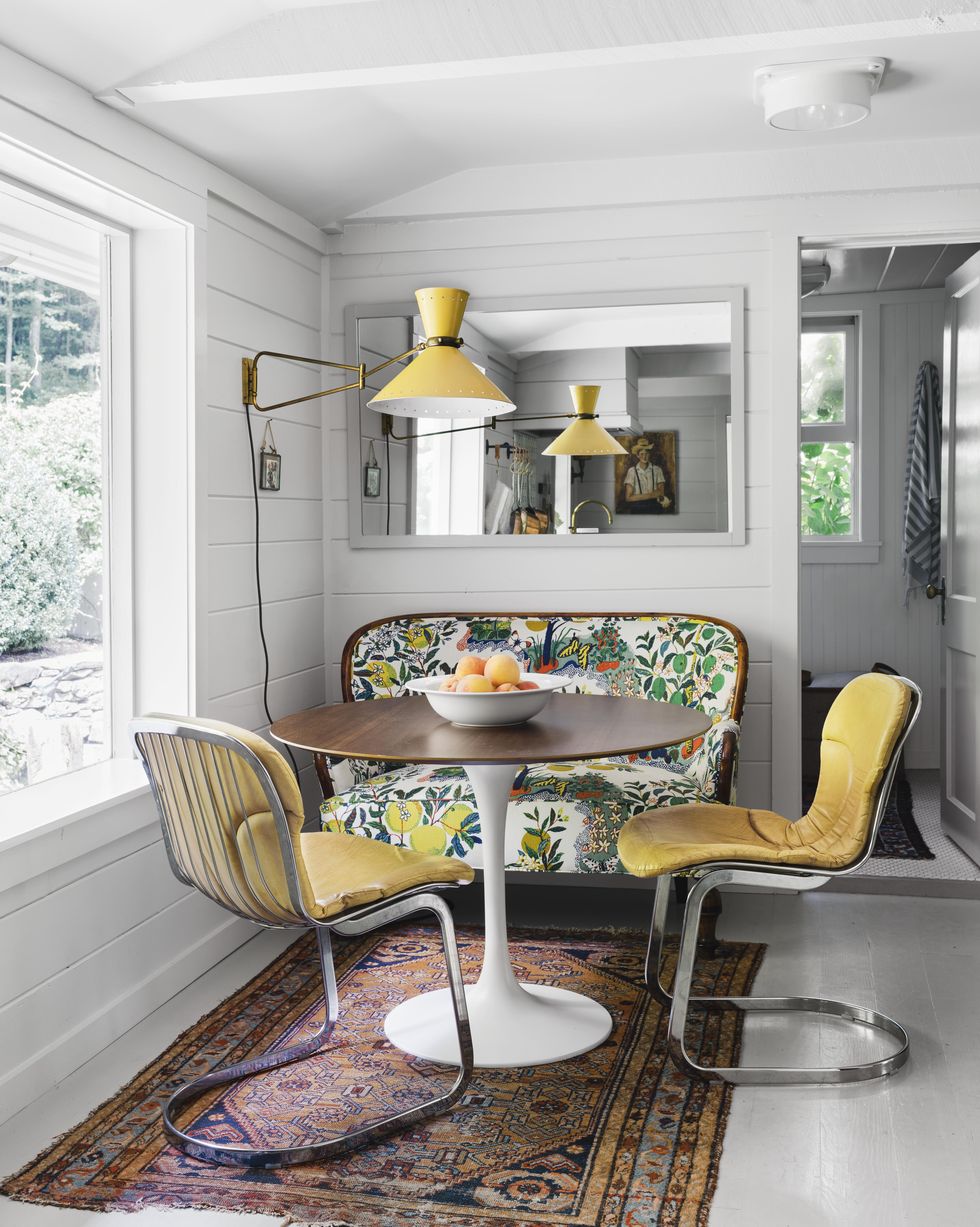 white dining nook with yellow midcentury chairs and sconce