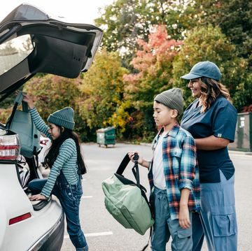 mom helping kids put stuff in the car