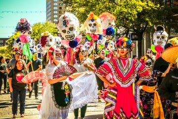 day of the dead festival parade with people in skeleton face paint