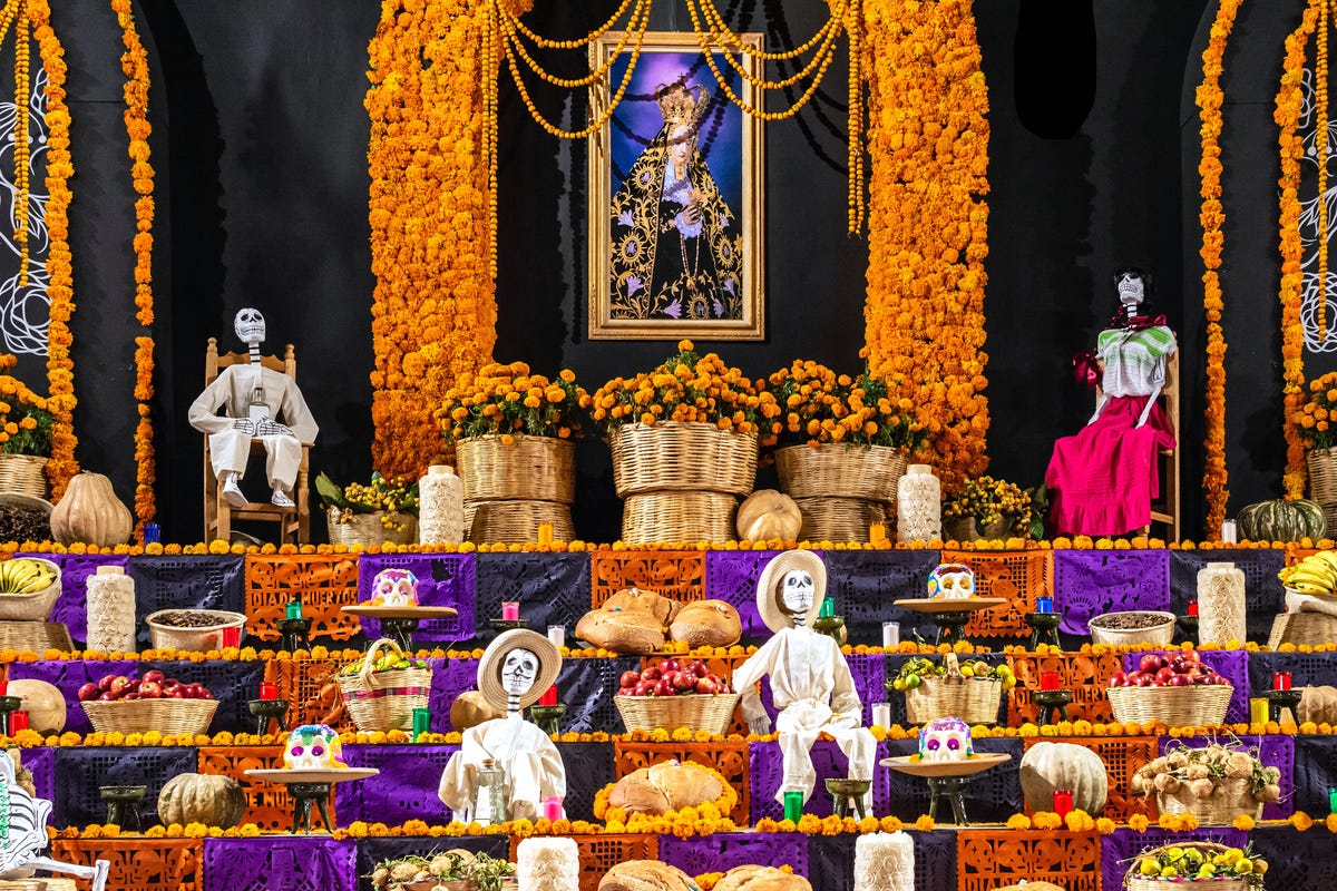 a day of the dead altar with orange flowers, bread and skeletons