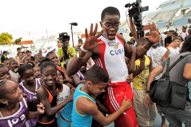 el exatleta cubano dayron robles levanta las manos rodeado de niños en una competición en la habana