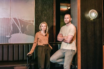 two people stand against a wall