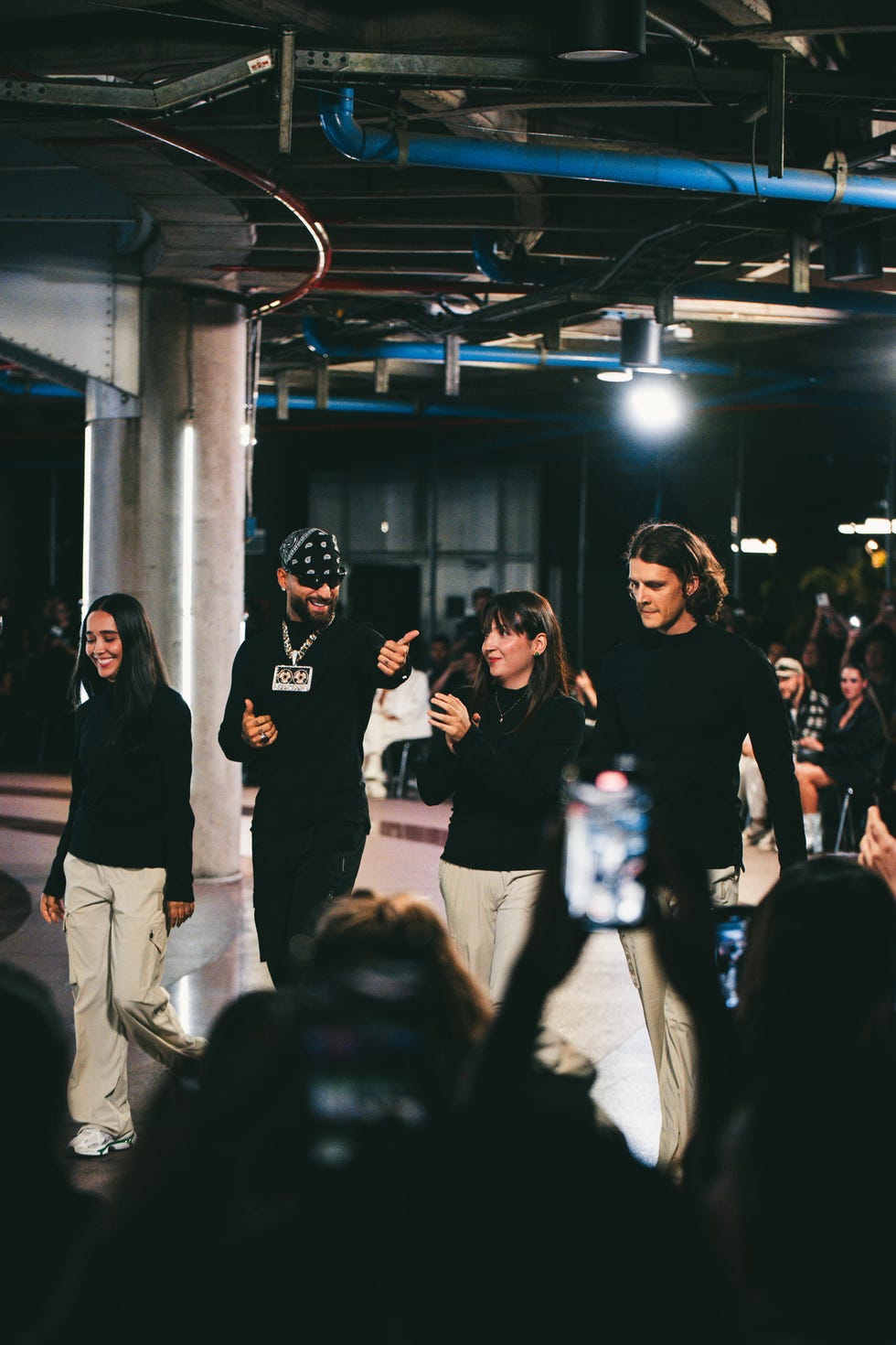 a group of individuals walking on a stage in a fashion show setting