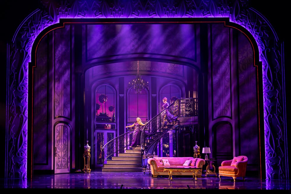 scene from a theatrical production featuring a staircase and ornate decor