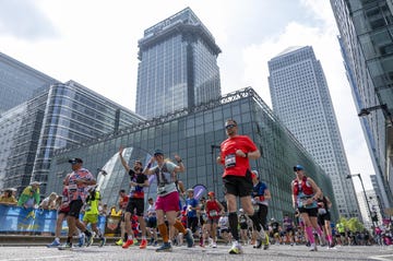 group people running through canary wharf during the 2025 tcs london marathon