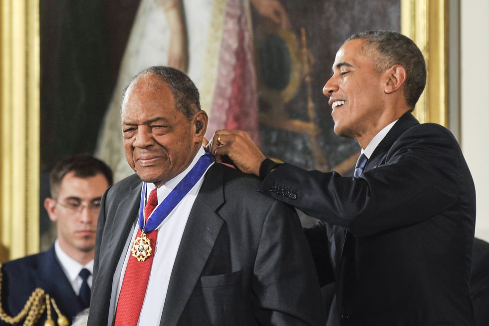 willie mays stands in front of barack obama who is placing a ribbon medal around willies neck, both men wear suits and smile