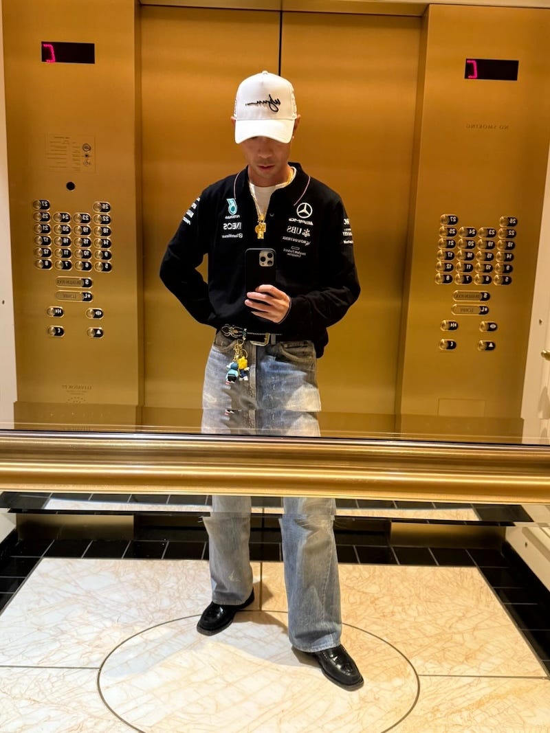 person taking a selfie in an elevator with golden panels and black flooring