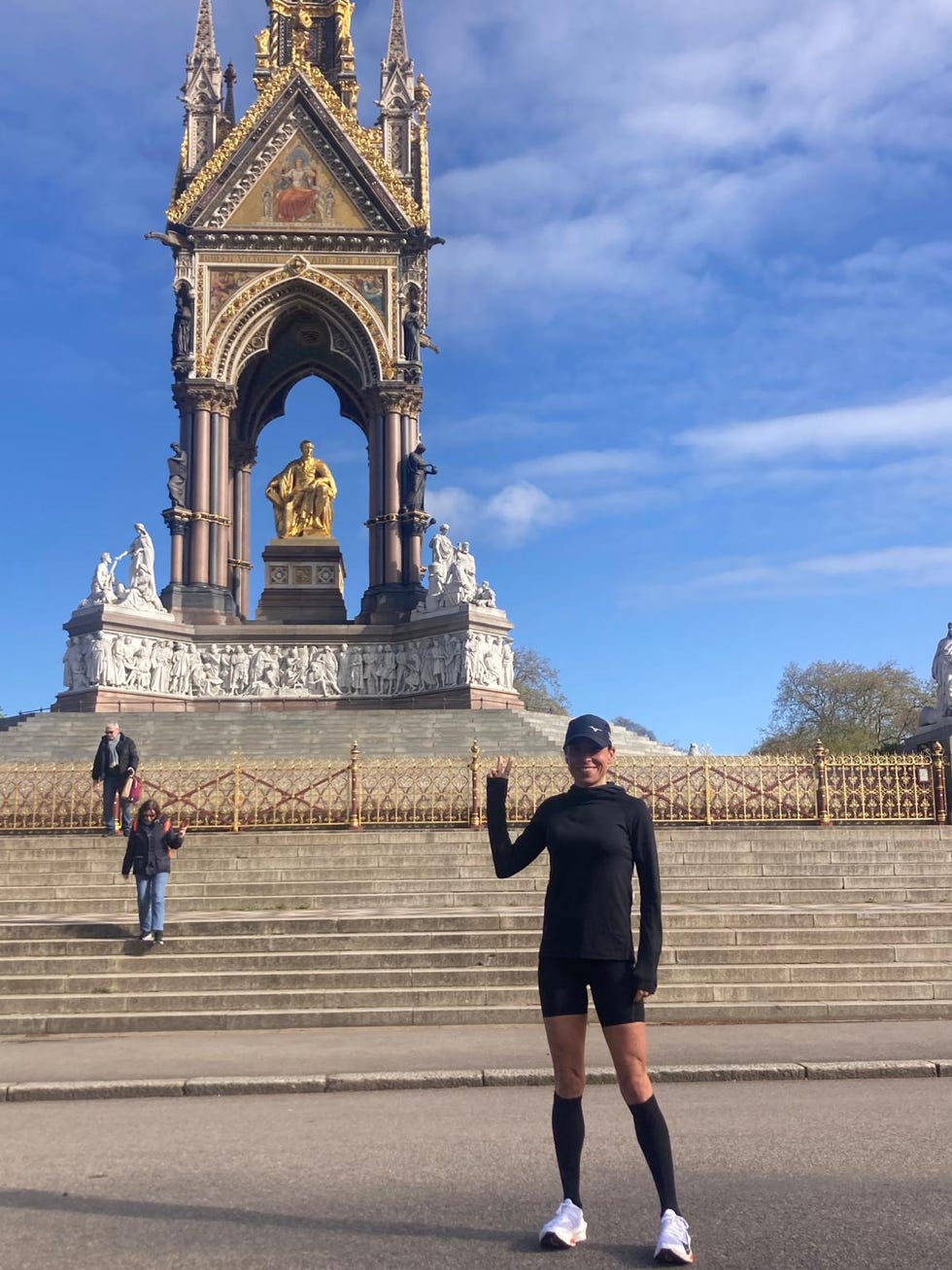 a person posing in front of a tall building with a gold statue