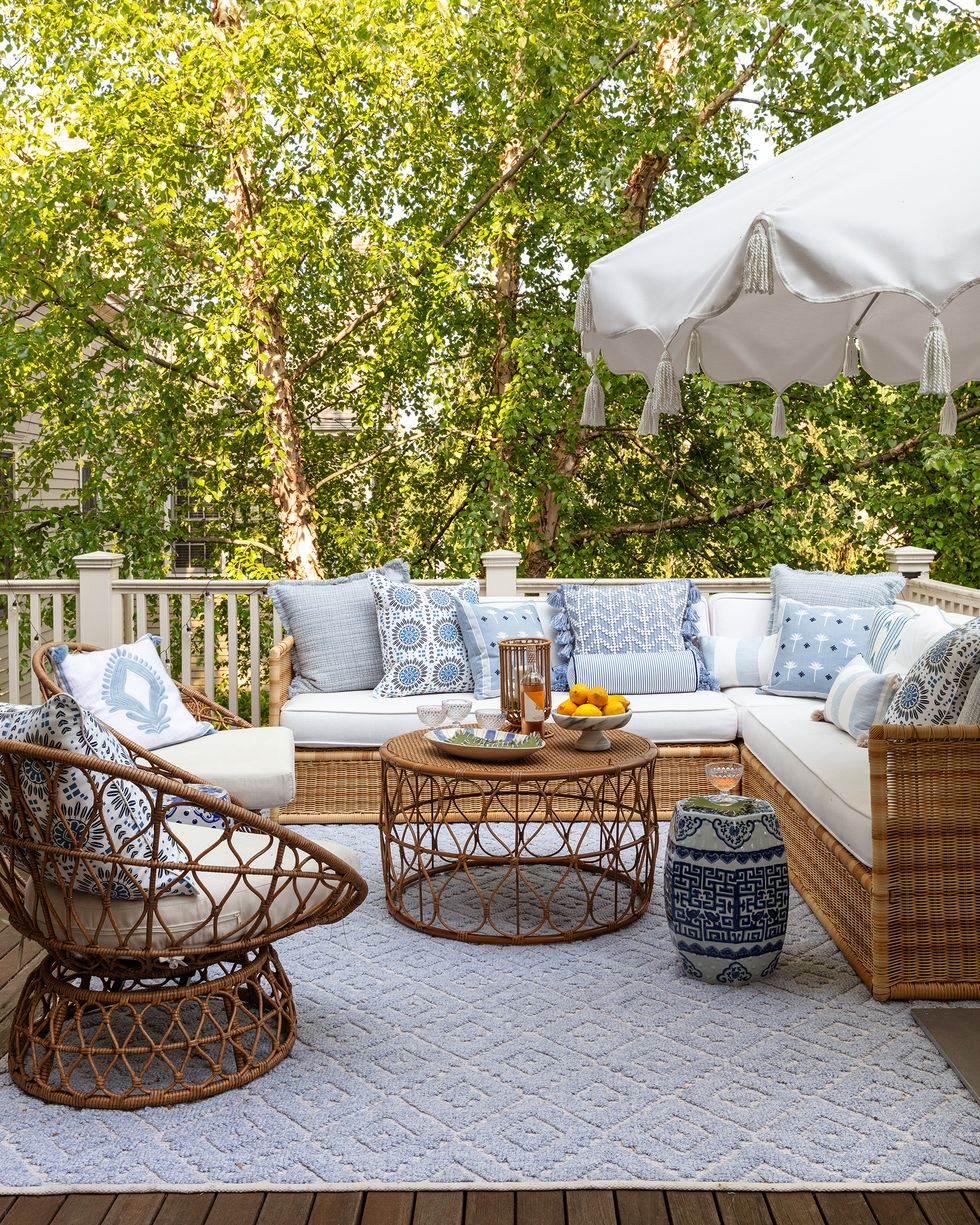outdoor couch, white seat cushions with range of blue and white decorative cushions, blue outdoor rug, blue and white side table