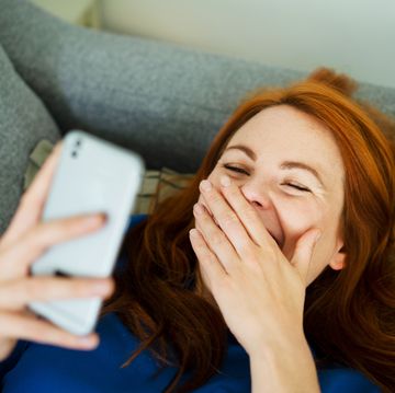 een vrouw lacht terwijl ze op haar telefoon kijkt