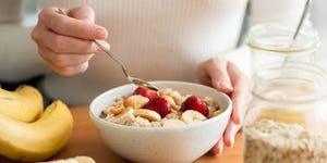 een vrouw eet havermout met banaan en aardbei