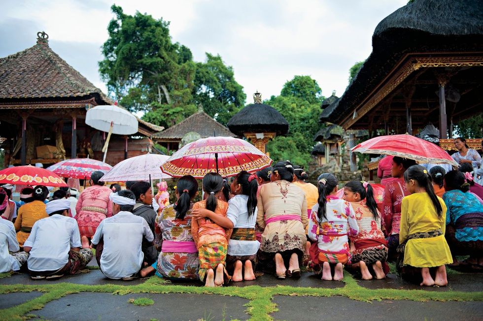 Tijdens het hoogtepunt van een boomkapceremnoie verzamelt de lokale bevolking zich op zn mooist uitgedost bij een heiligdom in Desa Tebuana