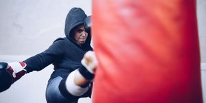 Young female kickboxer kicking punching bag at gym