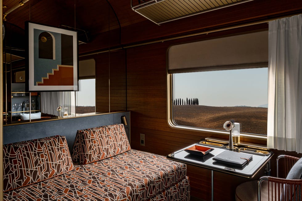 Interior of a stylish train cabin with a view of a rural landscape.