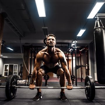 muscular fitness man doing deadlift a barbell over his head in modern fitness center functional training snatch exercise