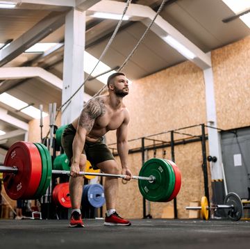 athletic shirtless man performing deadlift in a gym on a cross training