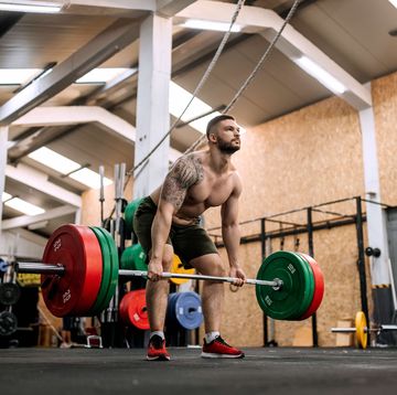 athletic shirtless man performing deadlift in a gym on a cross training