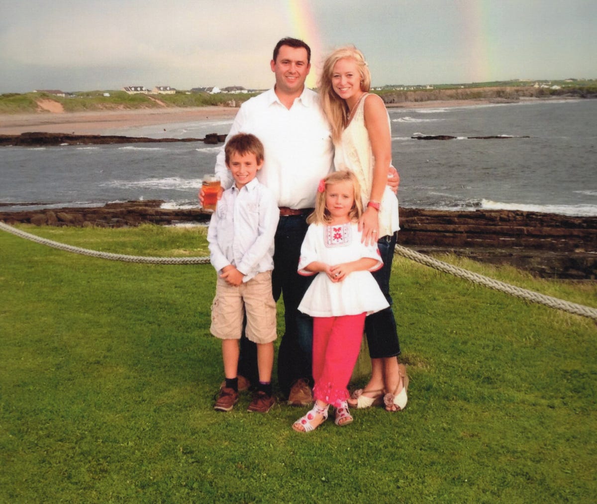 family standing in front of the ocean with a rainbow in the sky