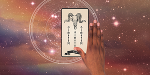 a hand with dark skin reaches out over a death tarot card, showing the skull of a horned animal the background is a dark, starry sky
