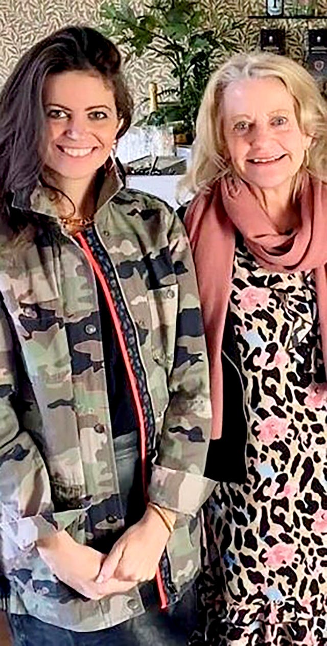 two women standing side by side one in camouflage and the other in a patterned dress