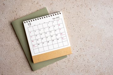 december 2022 desk calendar and green note pad on concrete background, top view