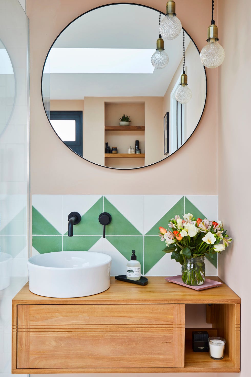 bathroom vanity area with a round mirror and white and green tiles