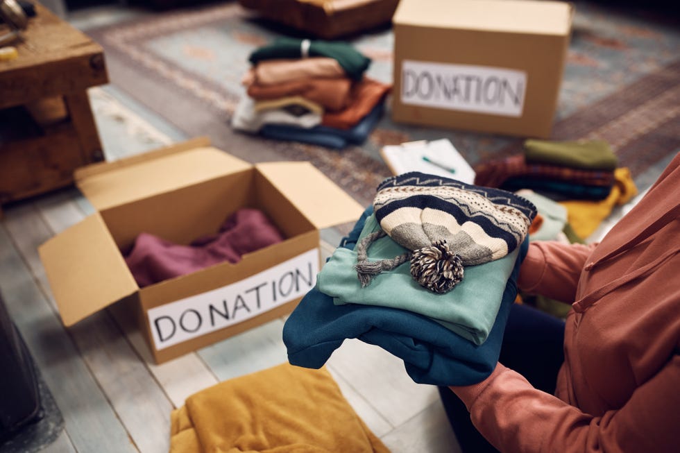 close up of woman packing boxes while donating her wardrobe for charity.