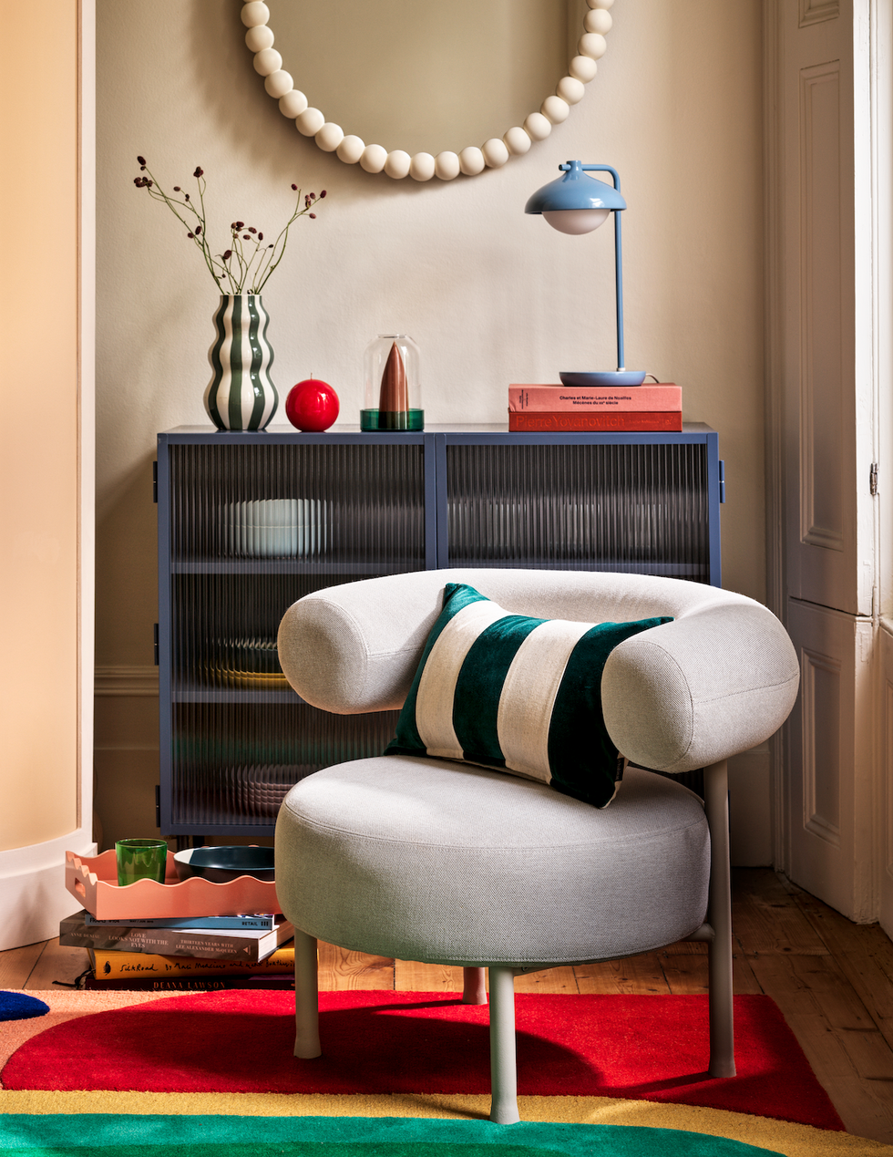 grey curved armchair with colourful abstract rug