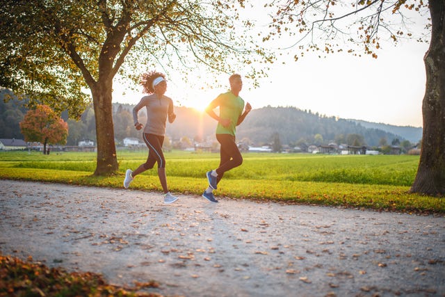 dedicated athletes running in public park at sunset