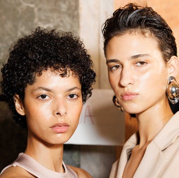 Models backstage at fashion week two individuals posing closely together in a fashion context