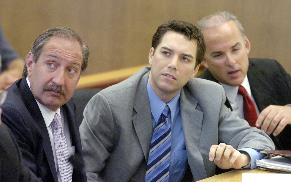 lawyer mark geragos, scott peterson, and lawyer pat harris sit at a table, all three men wear suit jackets, collared shirts and ties