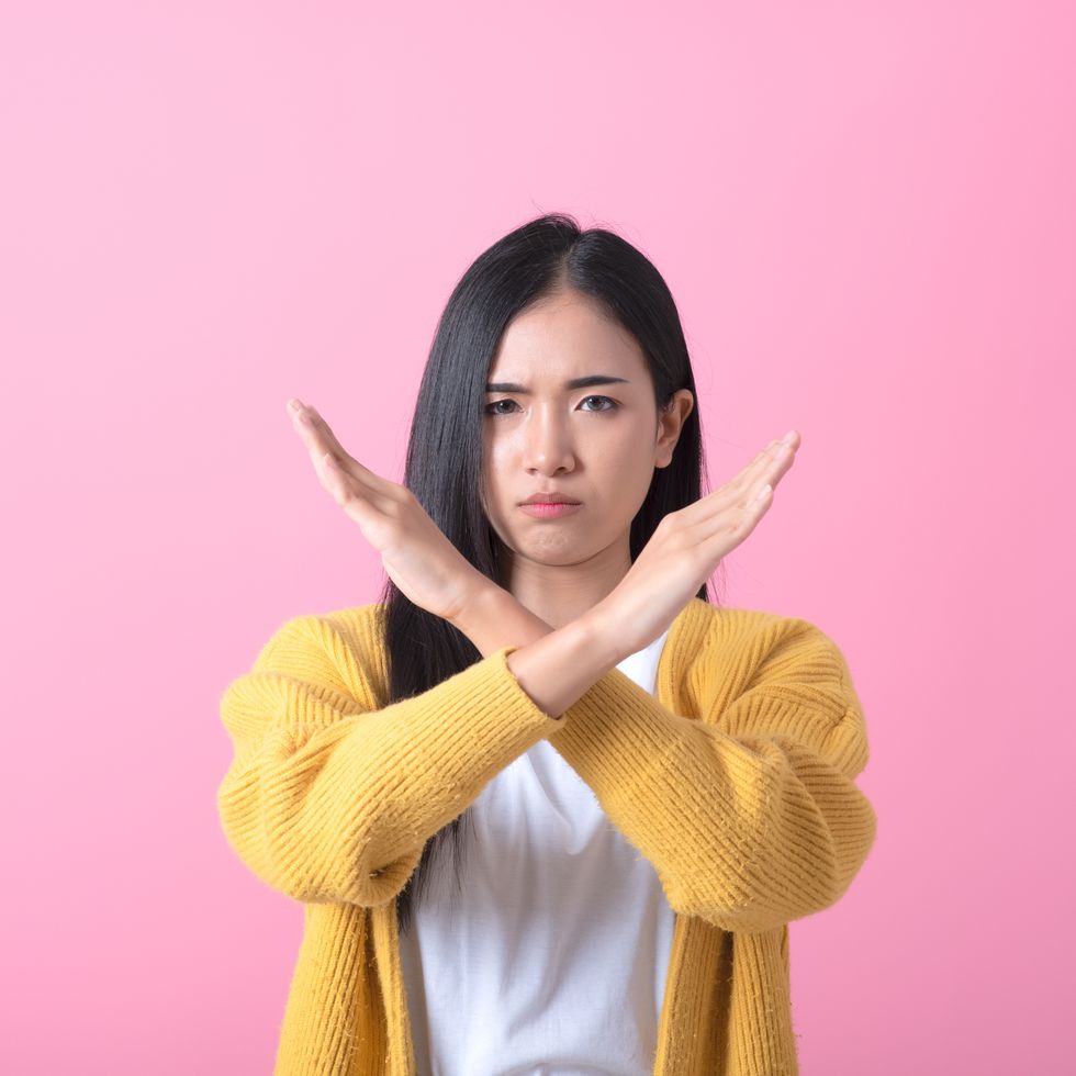 definitely no, prohibited access portrait of girl crossing hands, showing x sign, stop gesture, warning of end finish, forbidden way indoor studio shot isolated on pink background