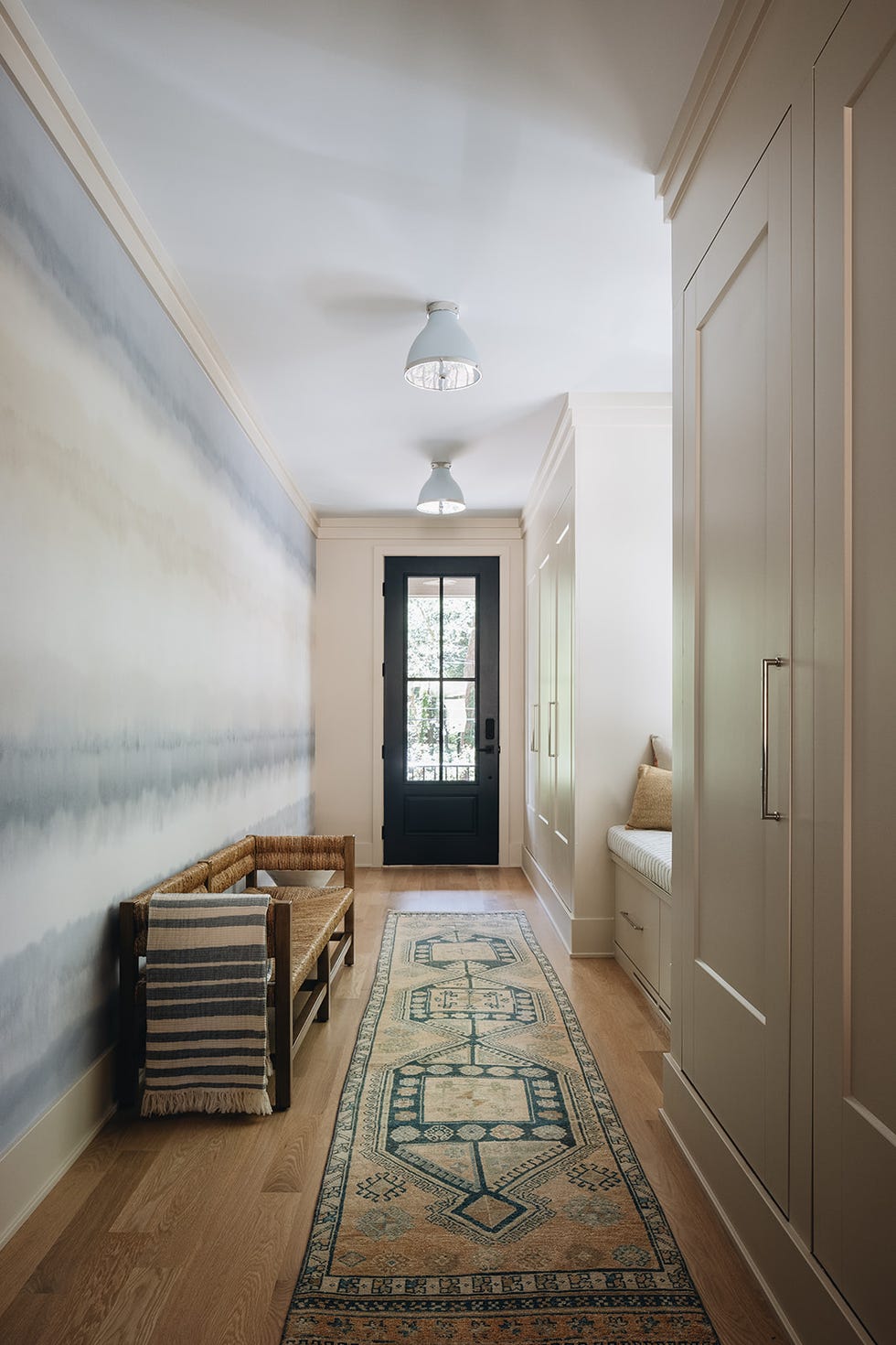 A hallway with a patterned rug bench and door