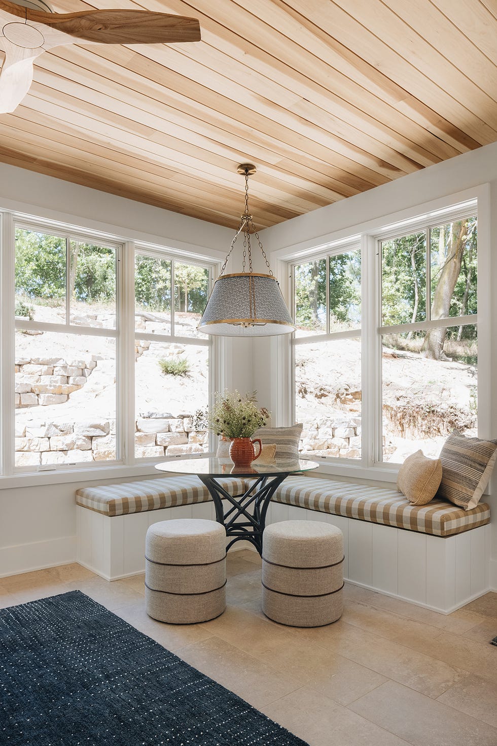 Cozy seating area with a round glass table patterned cushions and a pendant light