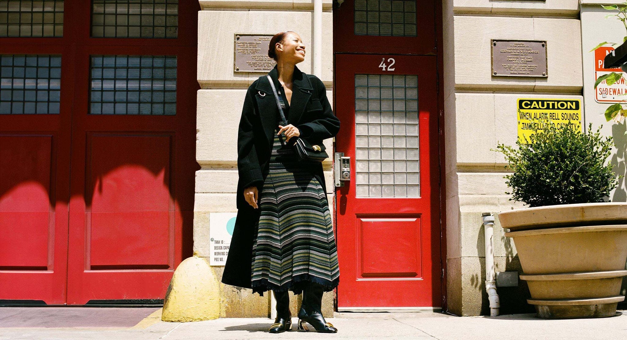 a model stands on a city street wearing a striped ribbed midi dress