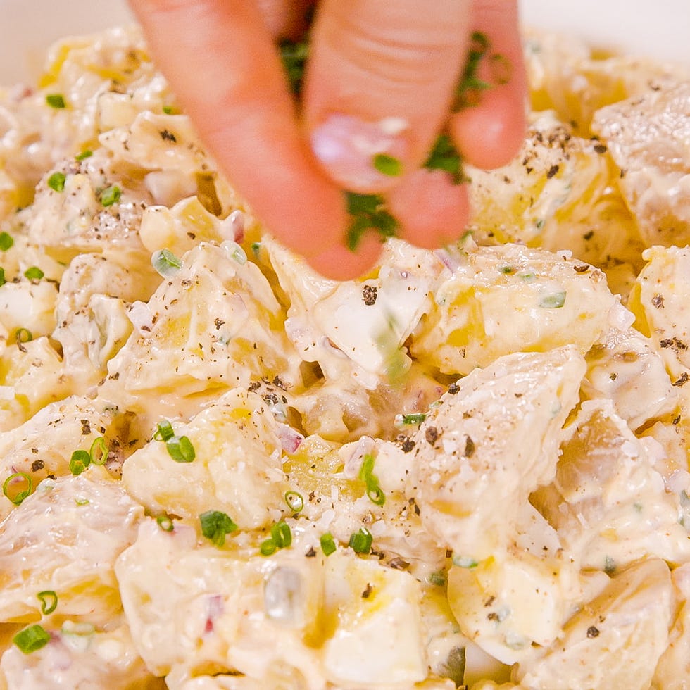 sprinkling chives on a potato salad
