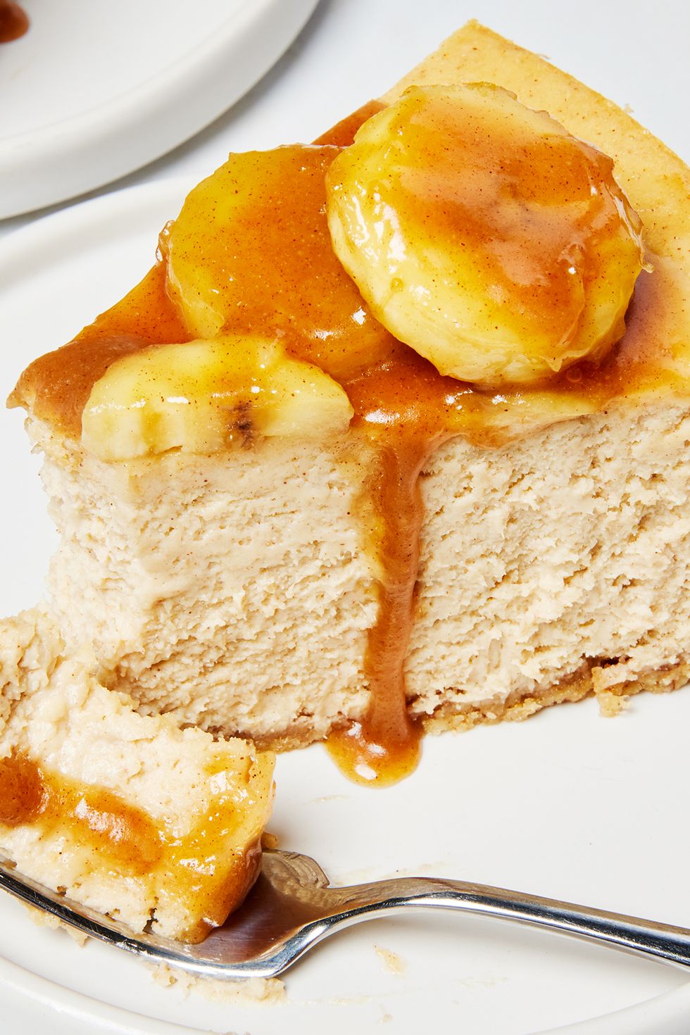 a slice of bananas foster cheesecake on a plate with a fork