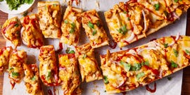 a loaf of french bread sliced in half and topped with shredded chicken, barbecue sauce, cheese, red onions, and cilantro