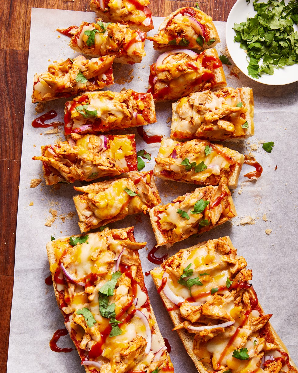 a loaf of french bread sliced in half and topped with shredded chicken, barbecue sauce, cheese, red onions, and cilantro