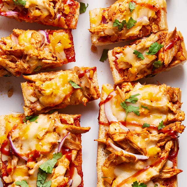 a loaf of french bread sliced in half and topped with shredded chicken, barbecue sauce, cheese, red onions, and cilantro