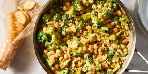 cheesy broccoli cheddar chickpeas in a skillet topped with ritz crackers with a pack of ritz crackers on the side