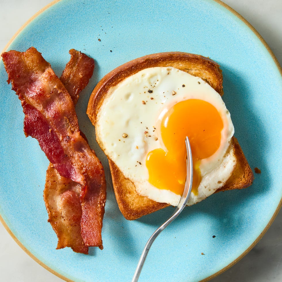 breakfast plate with a slice of toast topped with a fried egg and crispy bacon