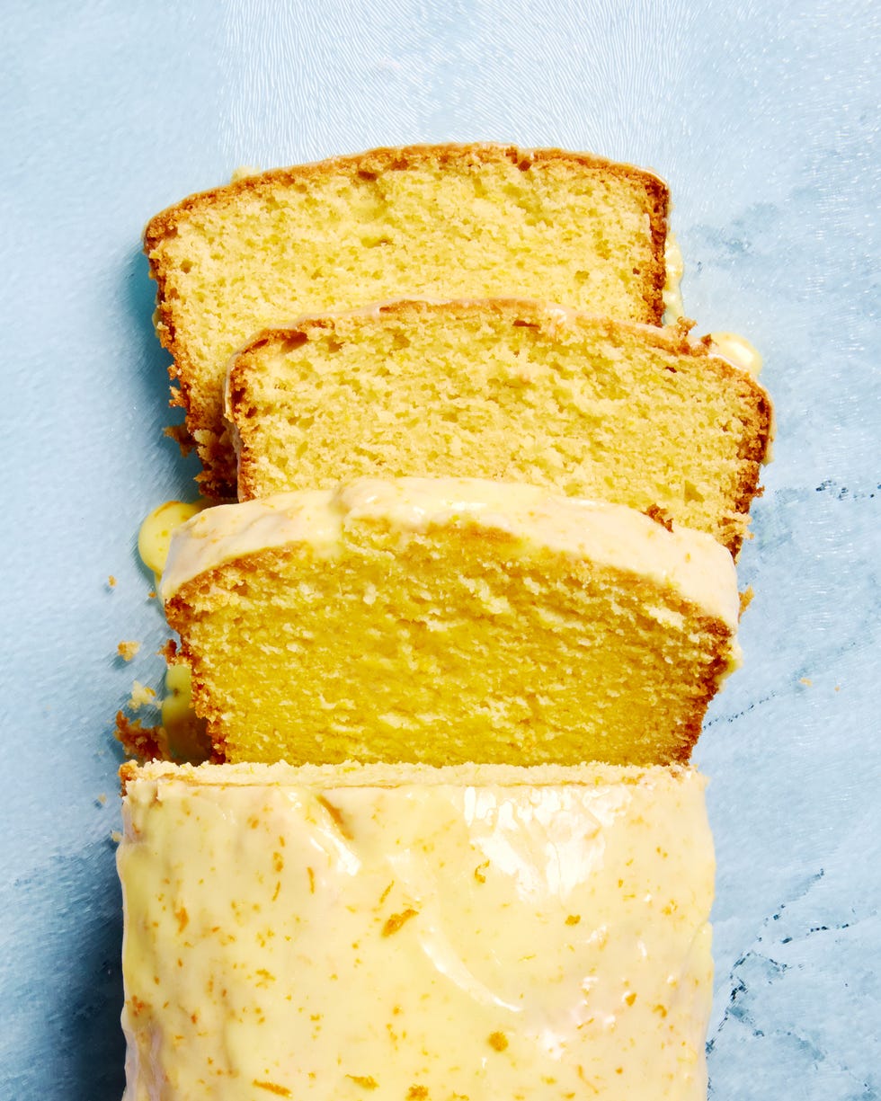 orange loaf cake glazed with orange icing on a blue glass cutting board